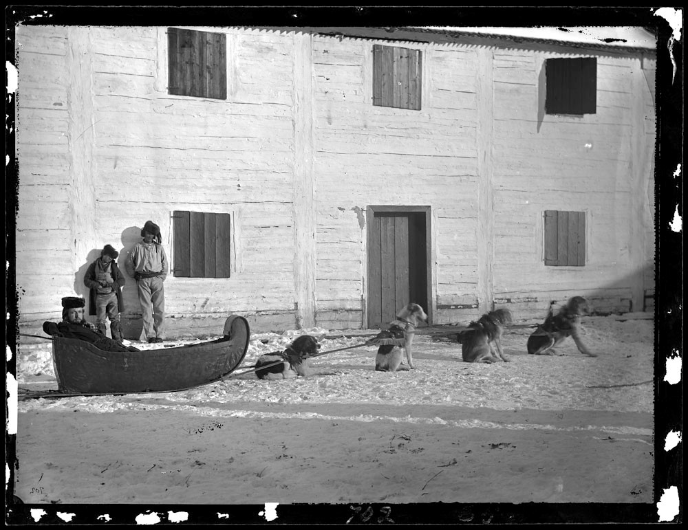 Three men and a Métis dog cariole, Fort Garry, Northwest Territories, 1871