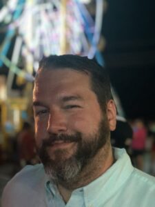 head shot of bearded man in front of abstract lights