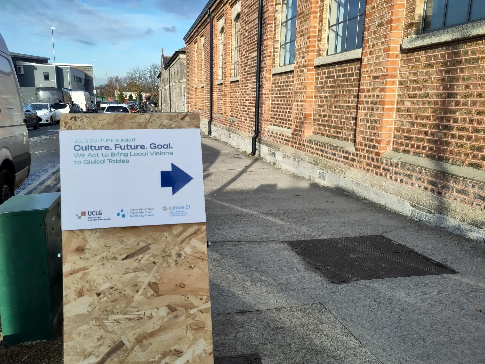 Sign for the Culture Summit - Culture Future Goal - on an MDF sign holder, pointing into a brick building