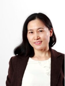 woman with dark hair wearing a white shirt and a black blazer on a white background
