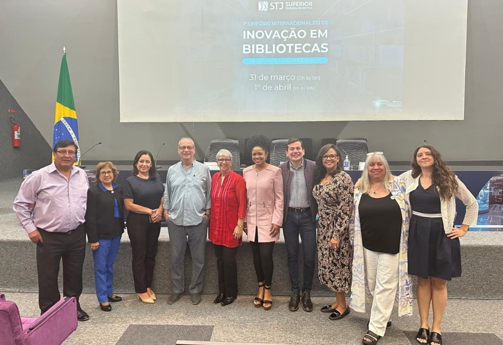 Group of people in front of a display screen, with a Brazilian flag