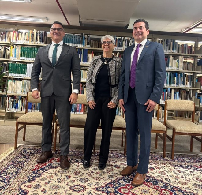 Group of three people in a library - two men on the left and right, and a woman in the middle