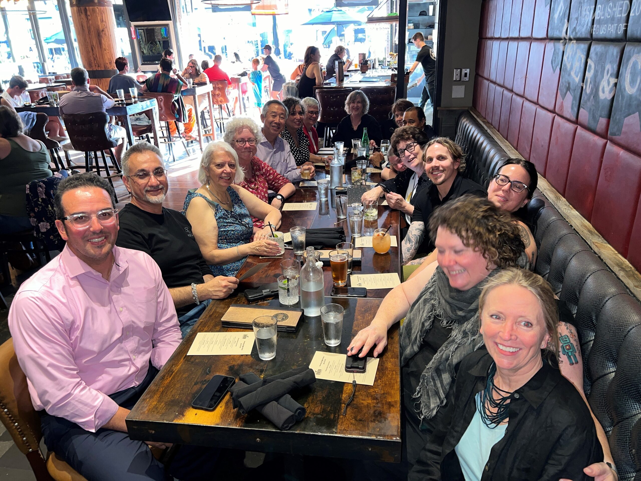 Group of smiling people around a table at a restaurant - mixture of men and women