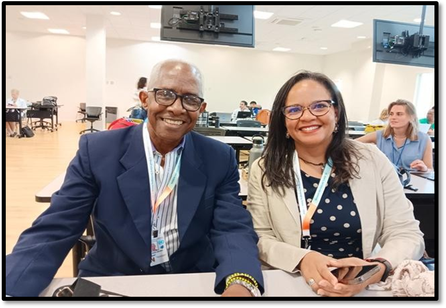 Two people smiling at a table with badges. A man on the left a woman on the right