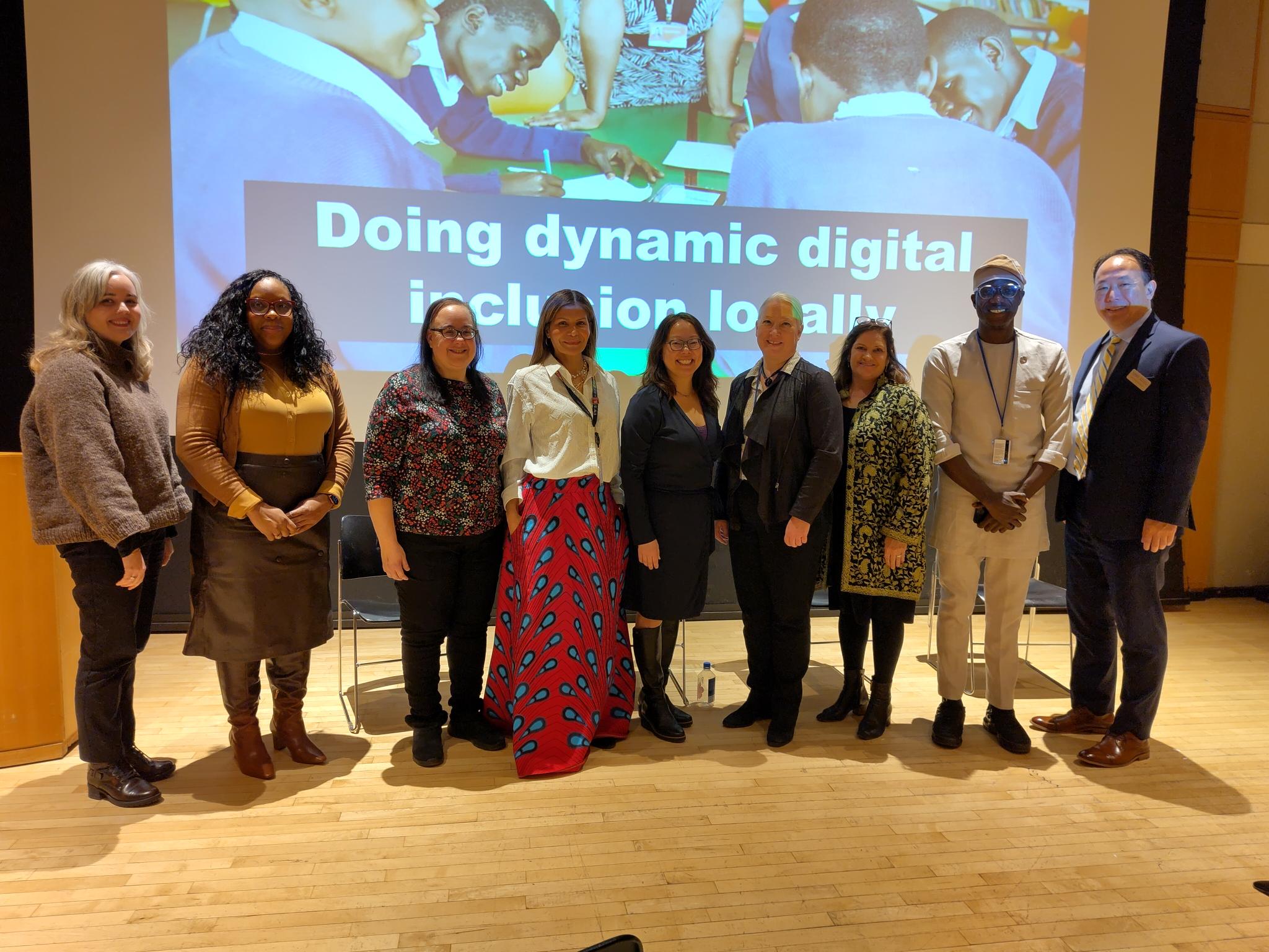 Group of people standing in front of a slide reading 'doing dynamic digital inclusion locally'. The people are from a mixture of backgrounds, including men and women.