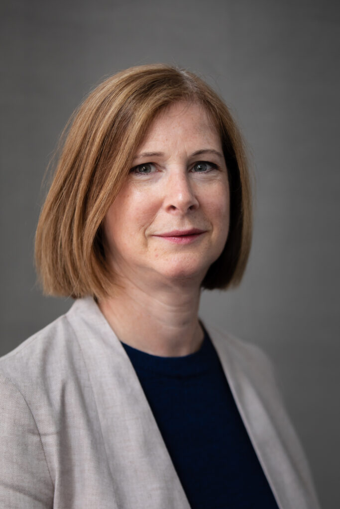 color photo (headshot) portrait of Debbie Schachter with grey background