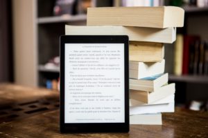 pexels perfecto capucine 1329571 300x200 An e book reader next to a pile of books